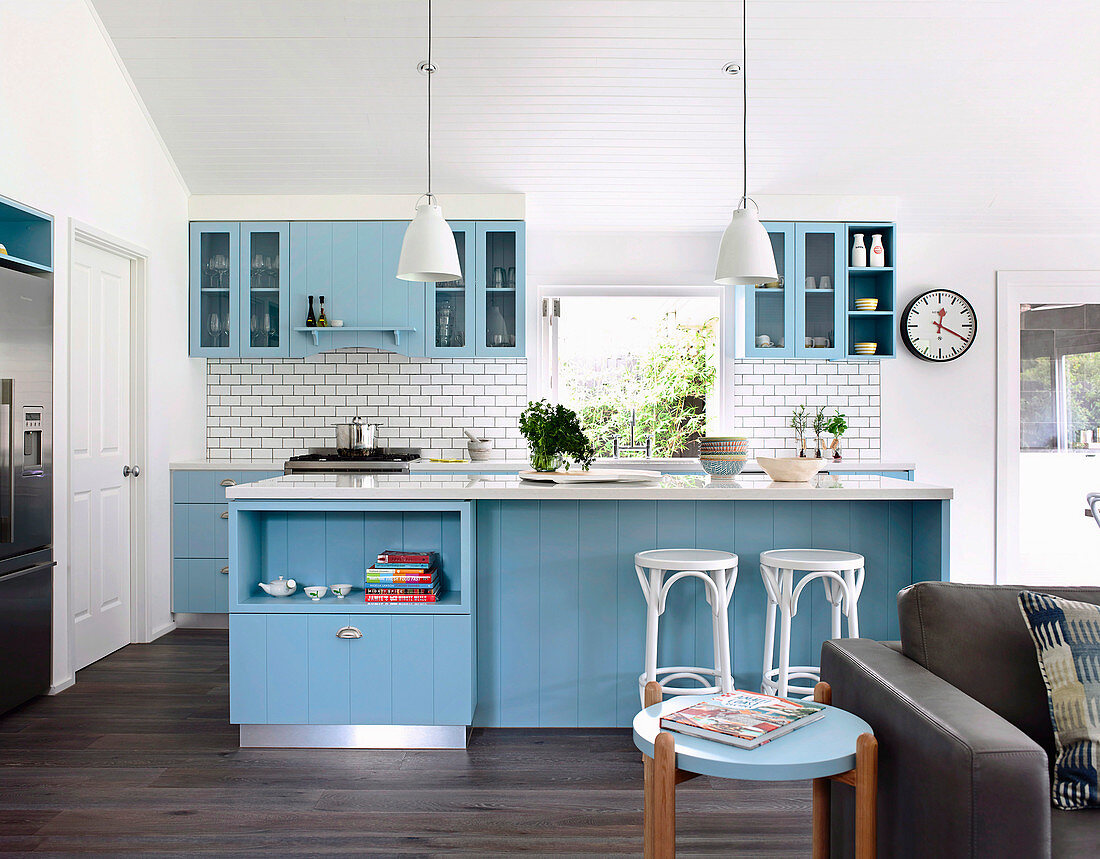 Offene Küche mit blauen Schrankfronten und weißen Wandfliesen