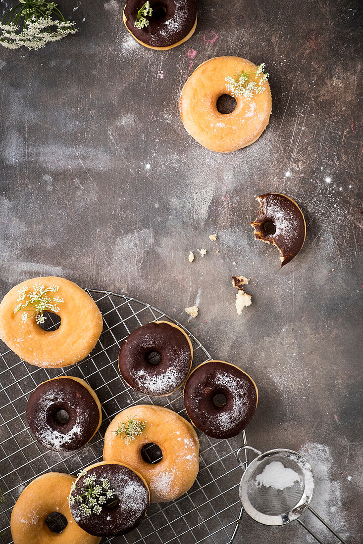 Donuts and chocolate donuts on a baking tray with powdered sugar and little white flowers