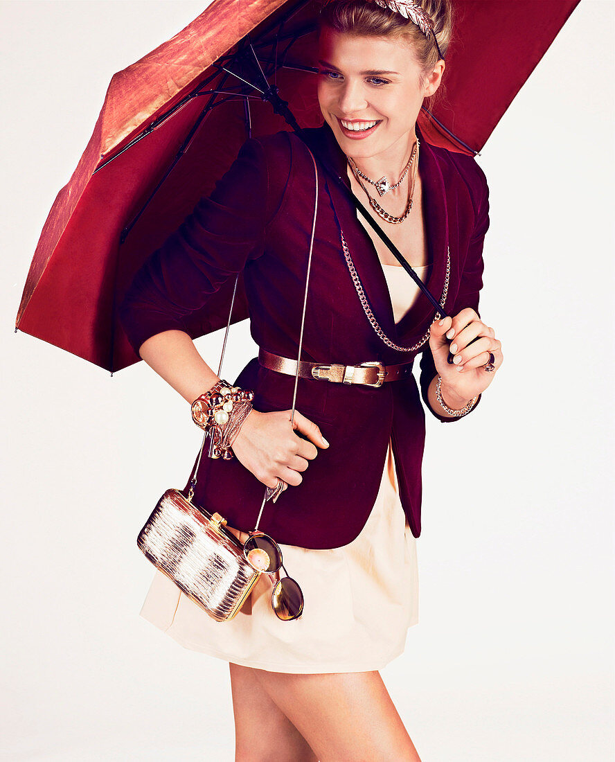 A young woman with an umbrella wearing a mini dress and a Bordeaux red blazer
