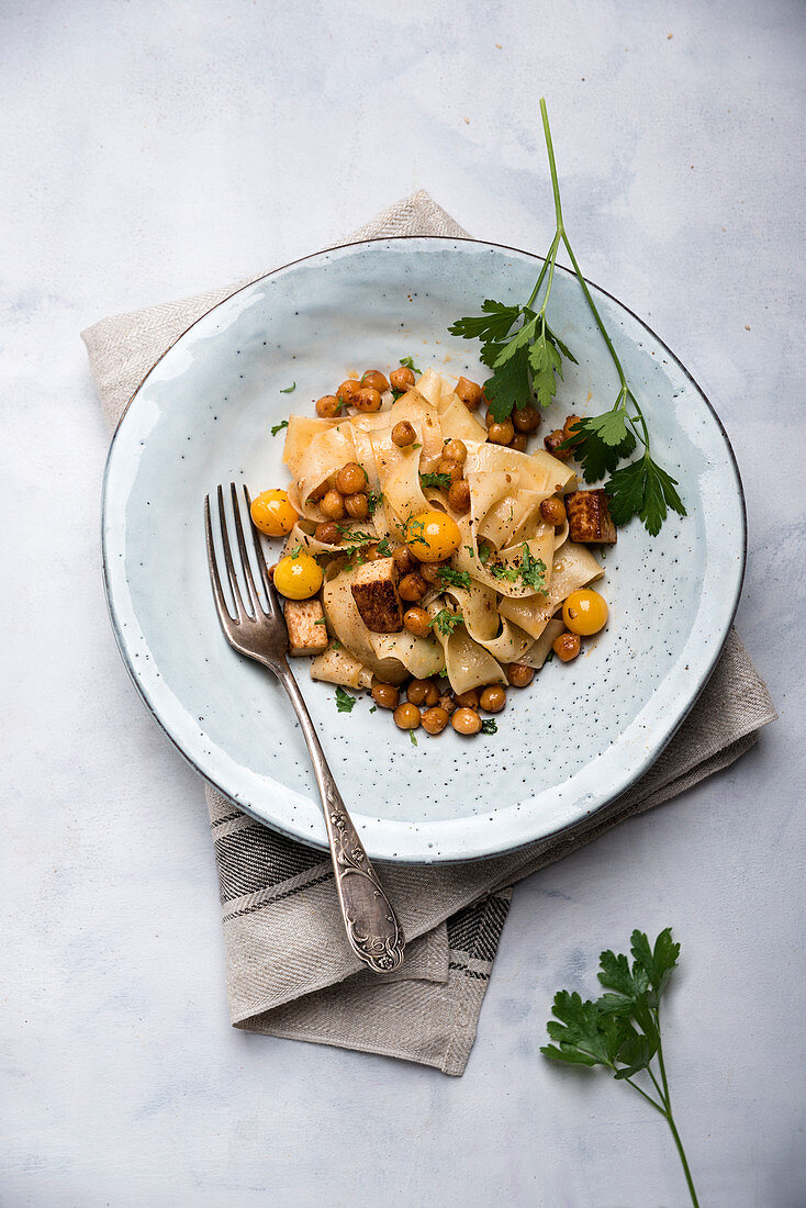 Vegan tagliatelle with fried tofu, chickpeas and yellow cocktail tomatoes