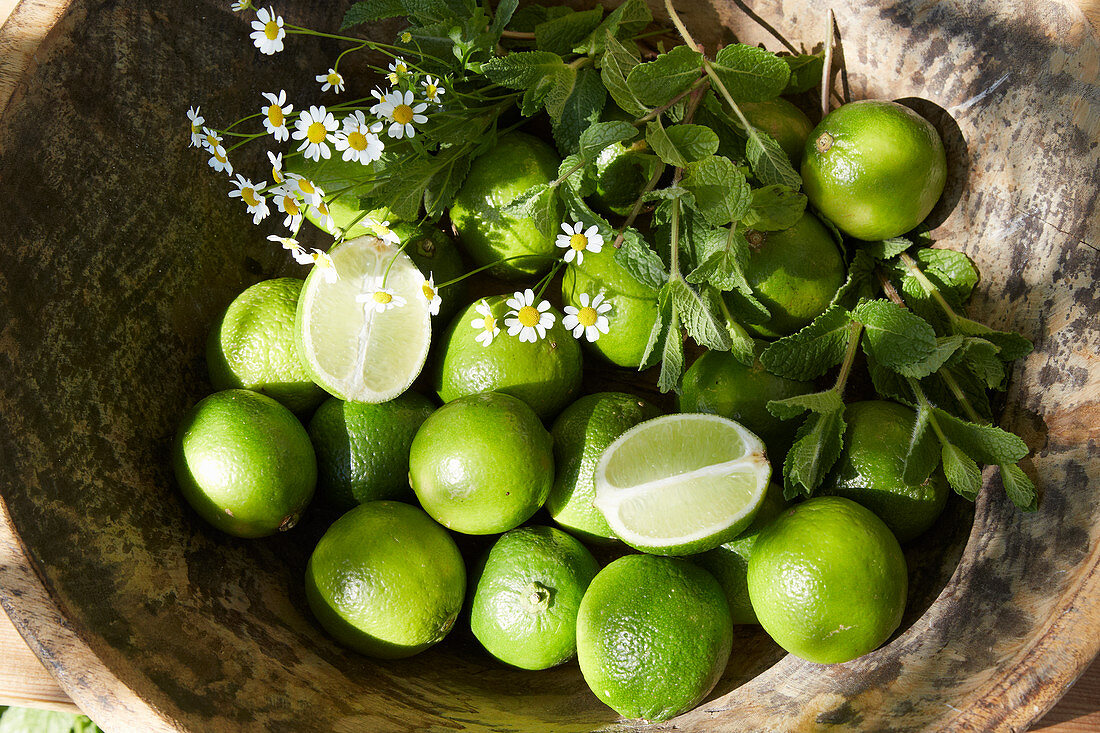 Posy of herbs and limes in wooden bowl