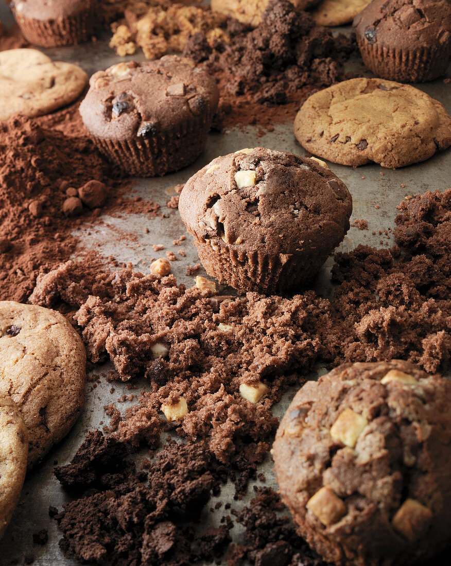 Cookies and muffins on a baking tray surronded by crumbs