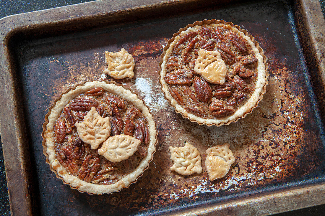 Two mini pecan pies on an oven sheet