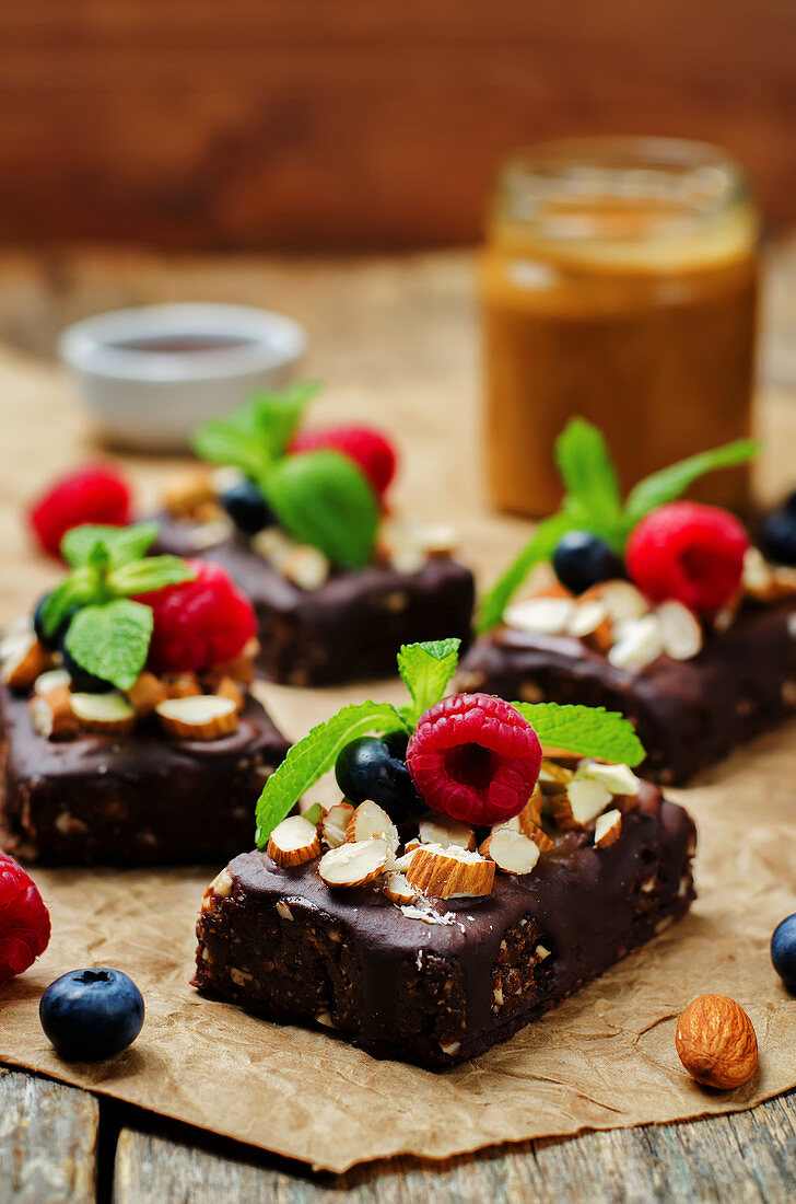 Raw vegan no bake chocolate, dates and almond brownies with chocolate frosting and berries