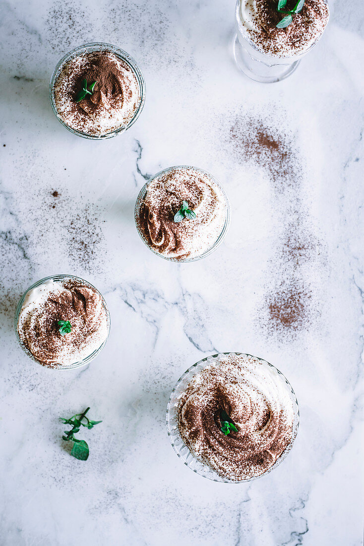 Tiramisu served in dessert glasses on a marble table (top view)