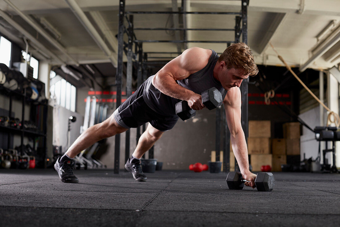 A young man performing a man maker small with dumbbells