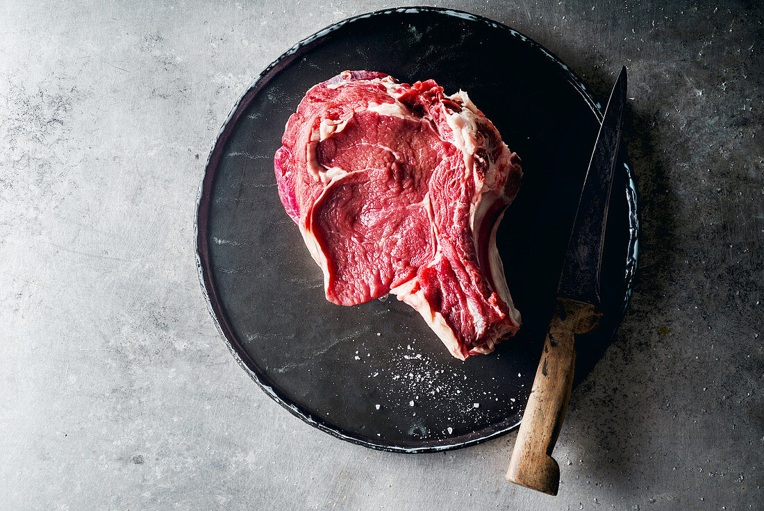 Rohes Rindersteak mit Messer auf Metalluntergrund