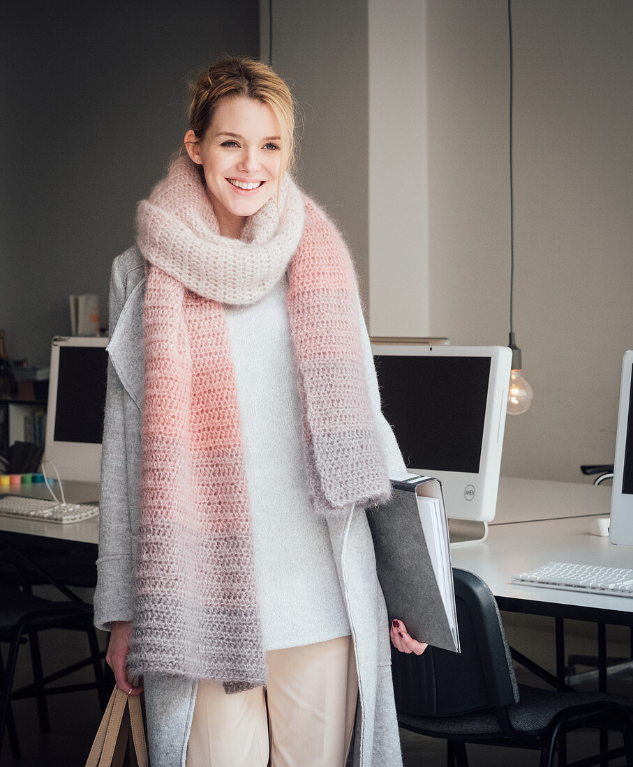 A blonde woman wearing a hand-crocheted, colour gradient scarf