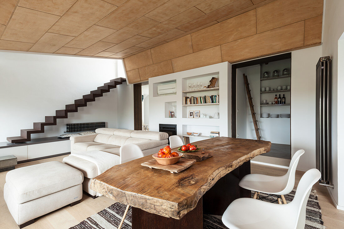 Rustic wooden table and classic chairs in front of sofa set in open-plan interior