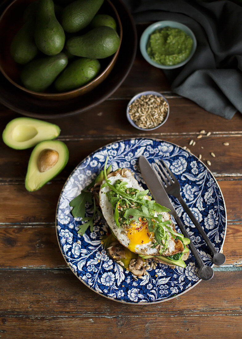 Toast mit Avocado, Spiegelei, Rucola und Sonnenblumenkernen