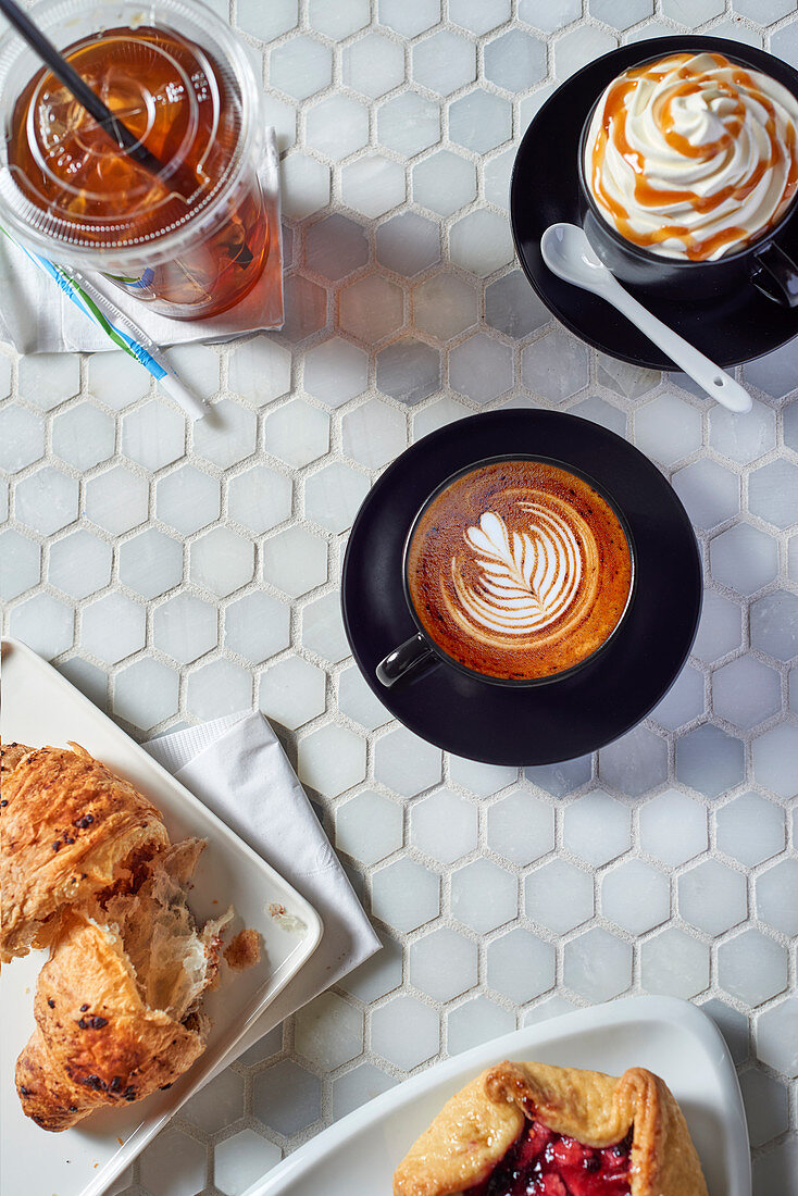 Various coffee drinks and sweet pastries on a table in a coffee bar