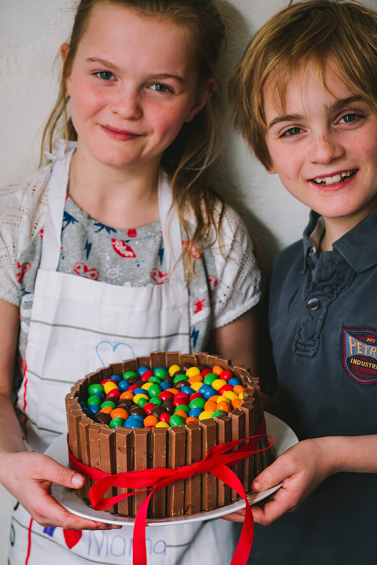 Kids made a Mother's Day cake with chocolate and candy, with a red ribbon