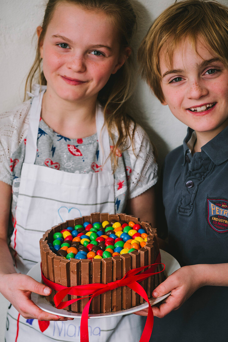 Kinder präsentieren selbstgemachten Muttertagskuchen