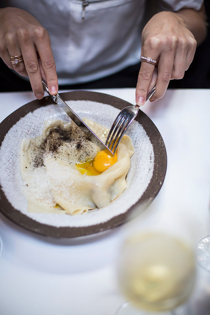 Frau isst Pasta mit Eigelb an Restauranttisch