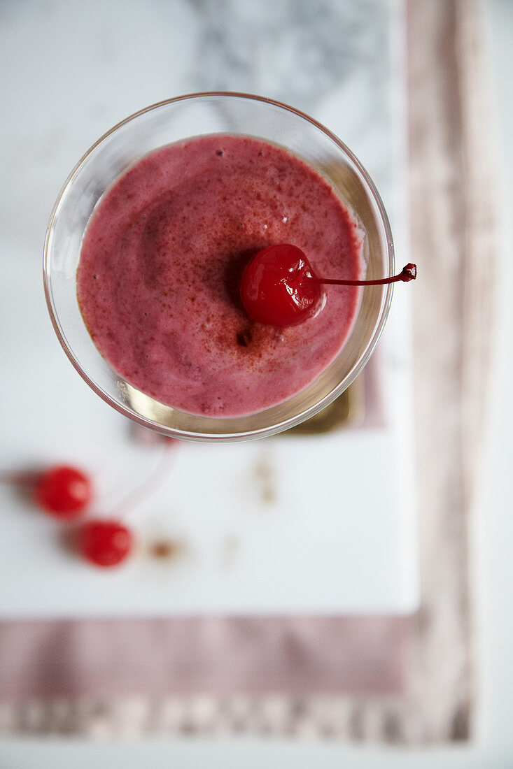 A yoghurt and raspberry drink with liquorice power and cocktail cherries