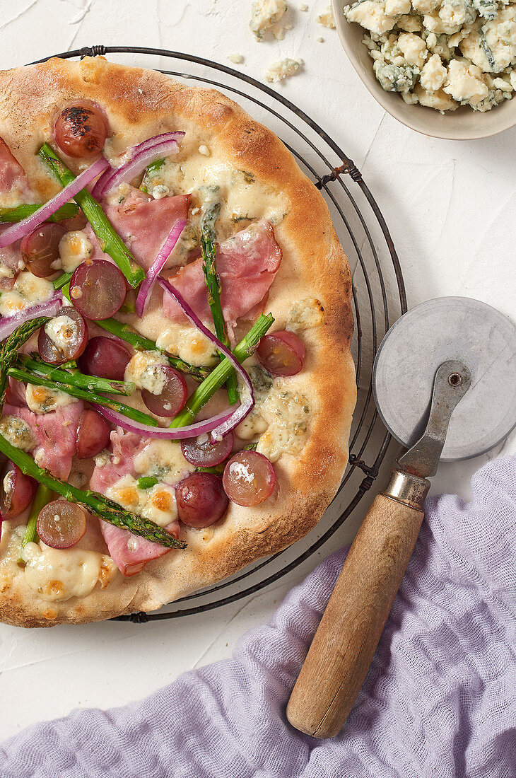 Pizza mit Schinken, Trauben, Spargel und Blauschimmelkäse