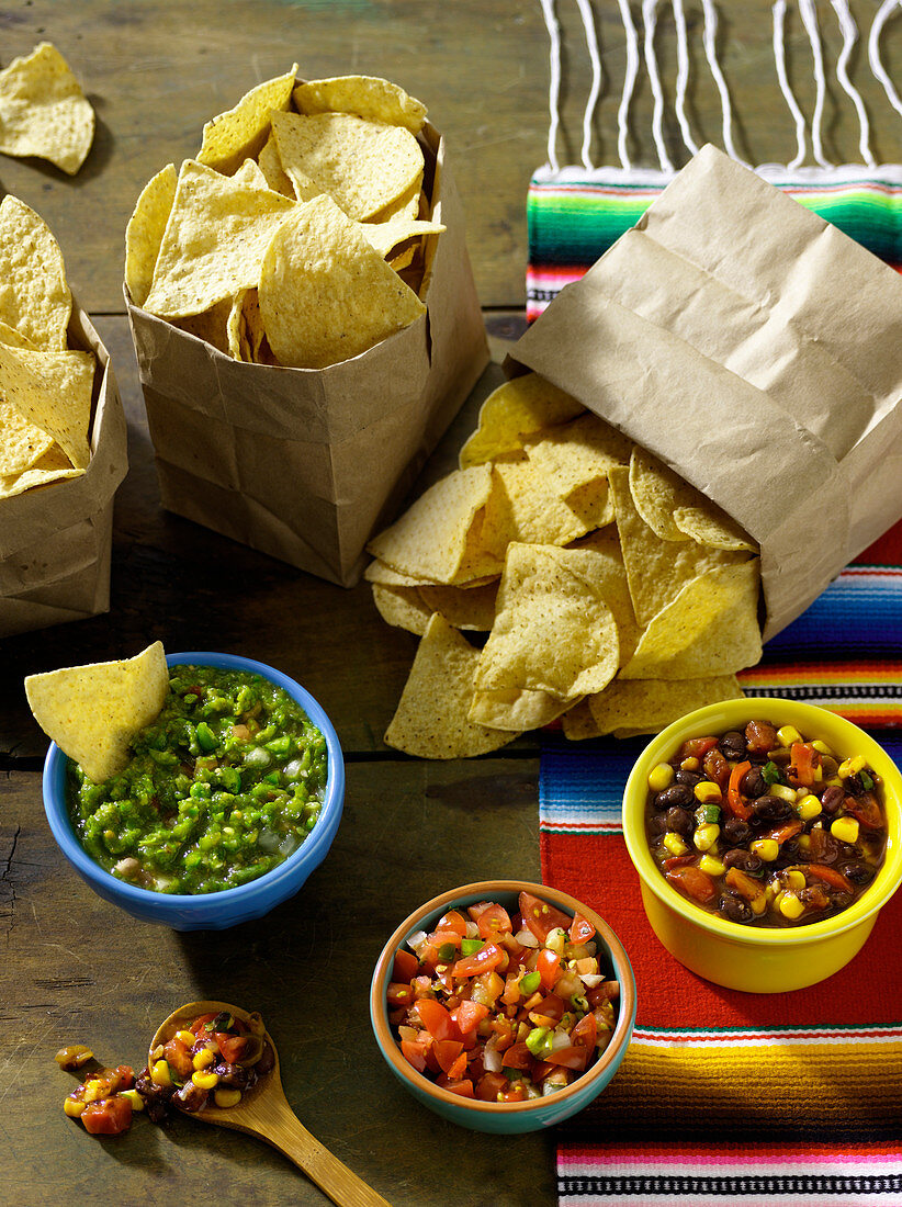 Drei Tüten Tortilla-Chips serviert mit dreierlei Salsa(Mexiko)