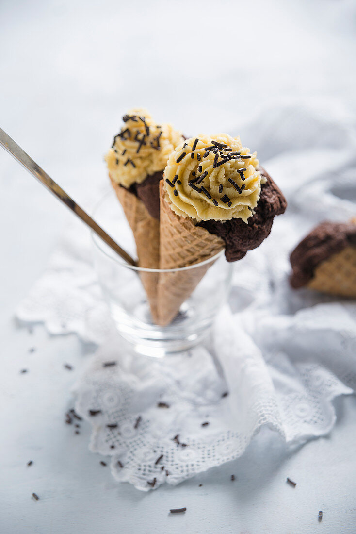 Im Waffelhörnchen gebackener Schokoladenkuchen, getoppt mit Karamellcreme und Zartbitterstreuseln (Vegan)