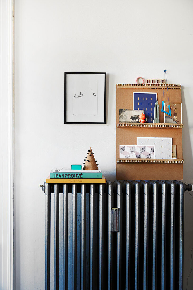 Various cards on DIY cardboard shelves on top of radiator