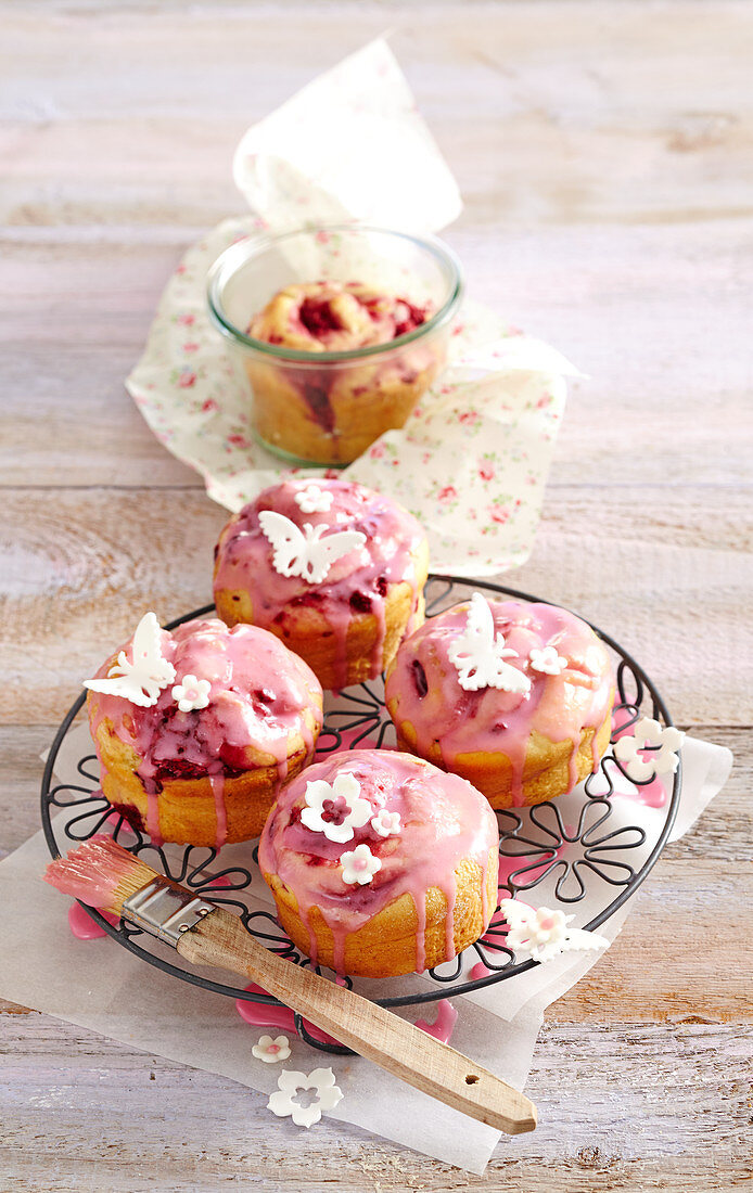 Mini raspberry cakes made from quark-oil dough decorated with icing and white fondant butterflies