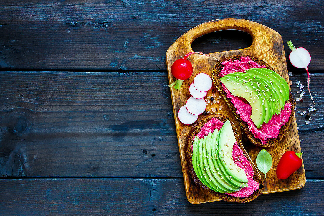 Vegan breakfast avocado and beet rye sandwiches, fresh radishes and sweet pepper
