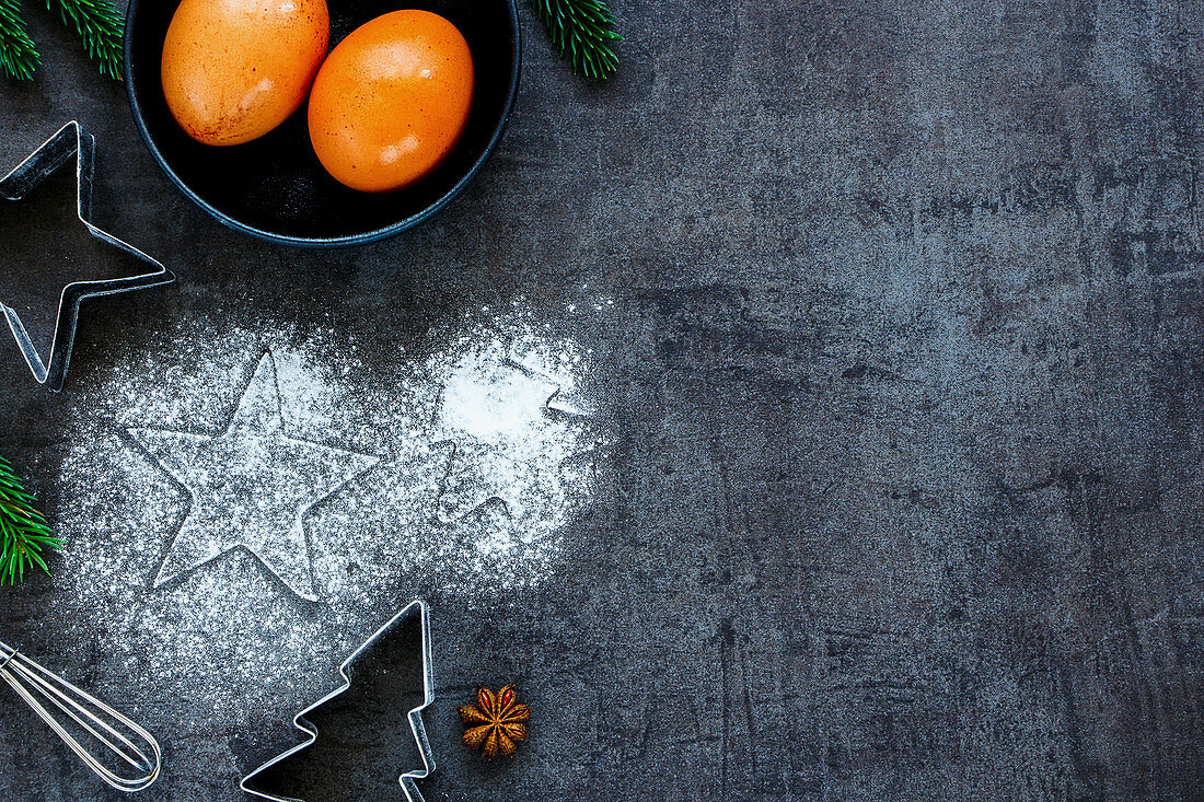 Christmas baking concept: cutters, anise star, eggs and whisk on kitchen table