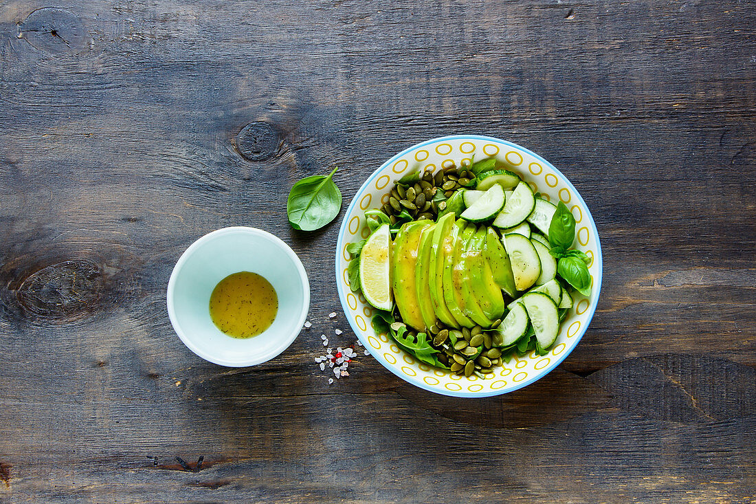 Veganer, grüner Sommersalat mit Avocado, Rucola, Gurken und Kürbiskernen