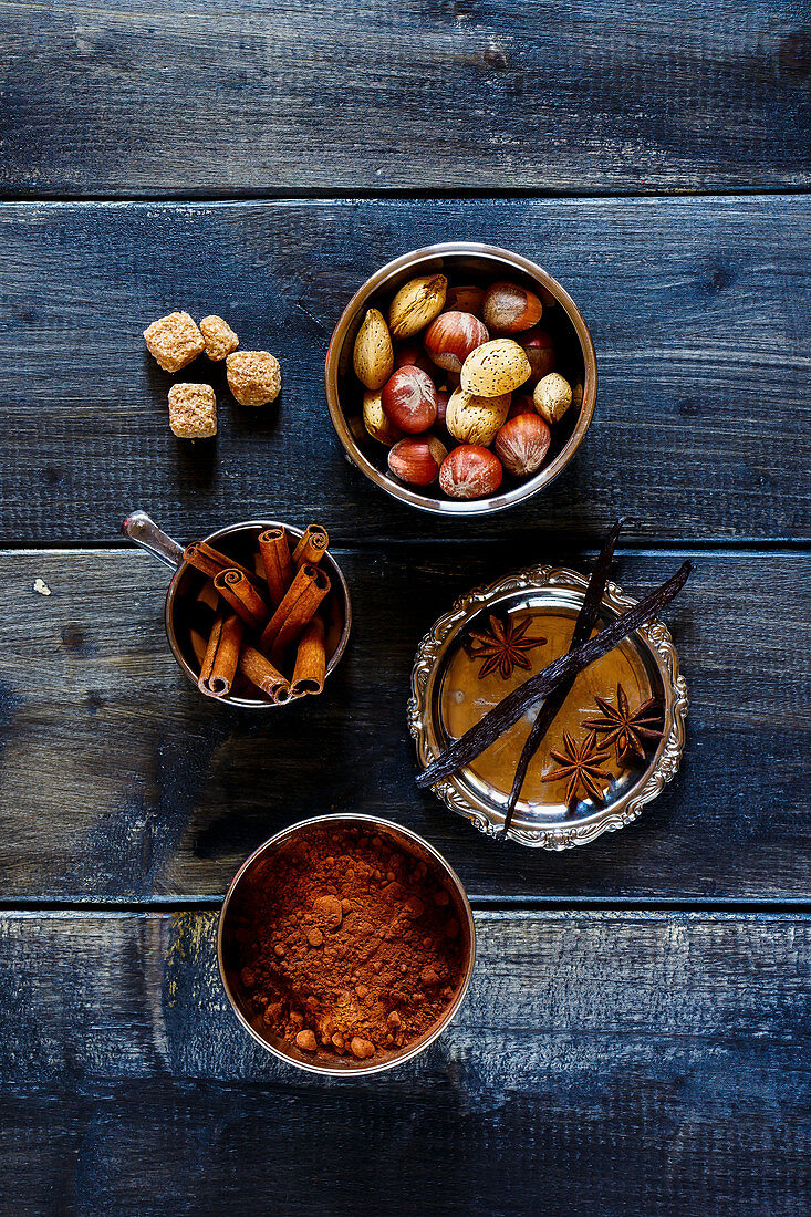 Assortment of aromatic spices and nuts for baking over dark wood background