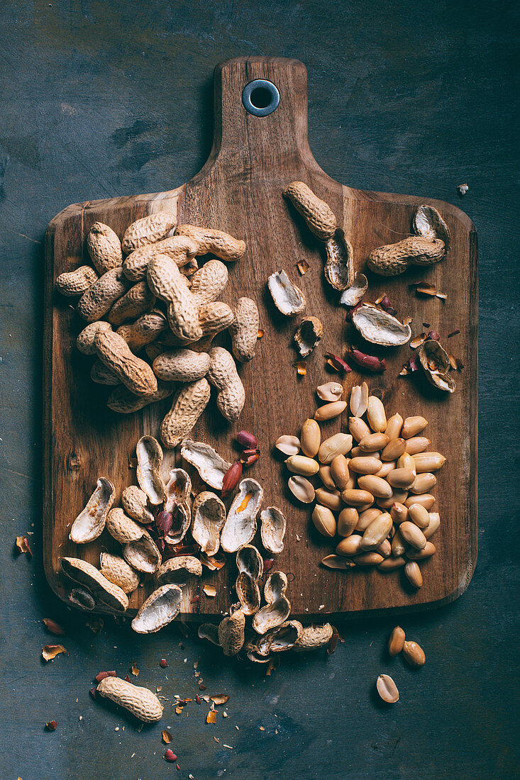 Erdnüsse, mit und ohne Schale auf Holzbrett (Aufsicht)