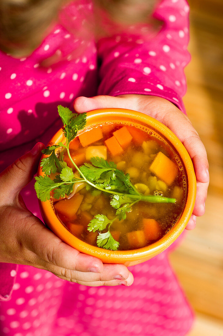 Child holds vegetable soup with split peas