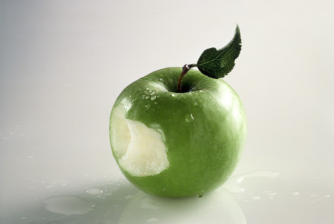 A Granny Smith Apple That Has Been Bitten; Water Drops
