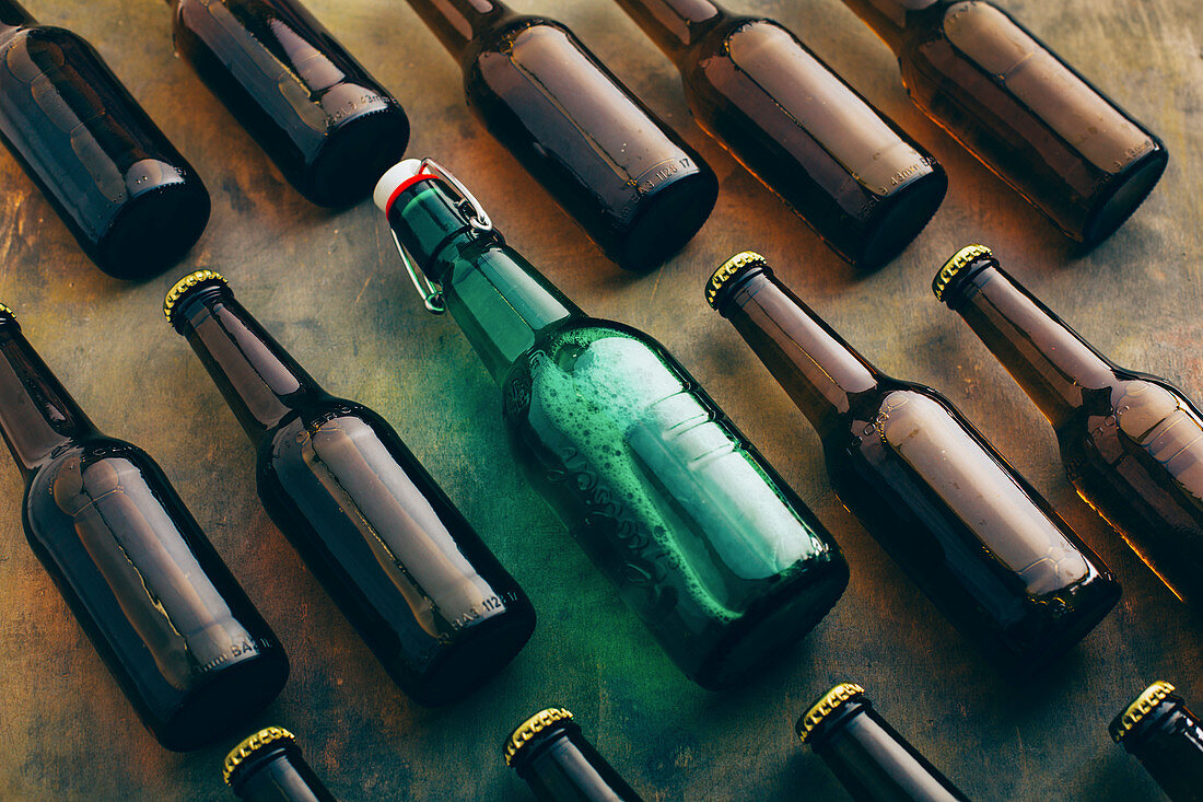 Viele braune Bierflaschen und eine grüne