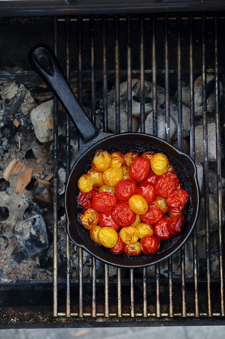 Yellow and red date tomatoes cooking over a grill (top view)