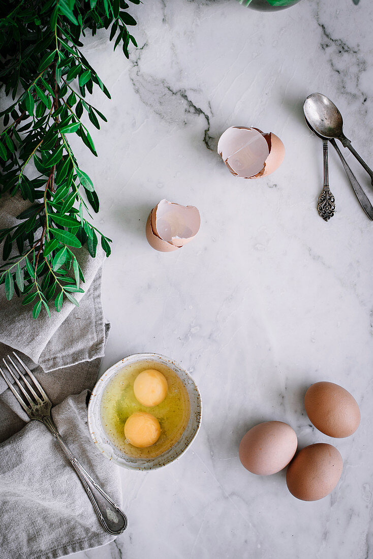 Schälchen mit aufgeschlagenen Eiern auf Marmortischplatte