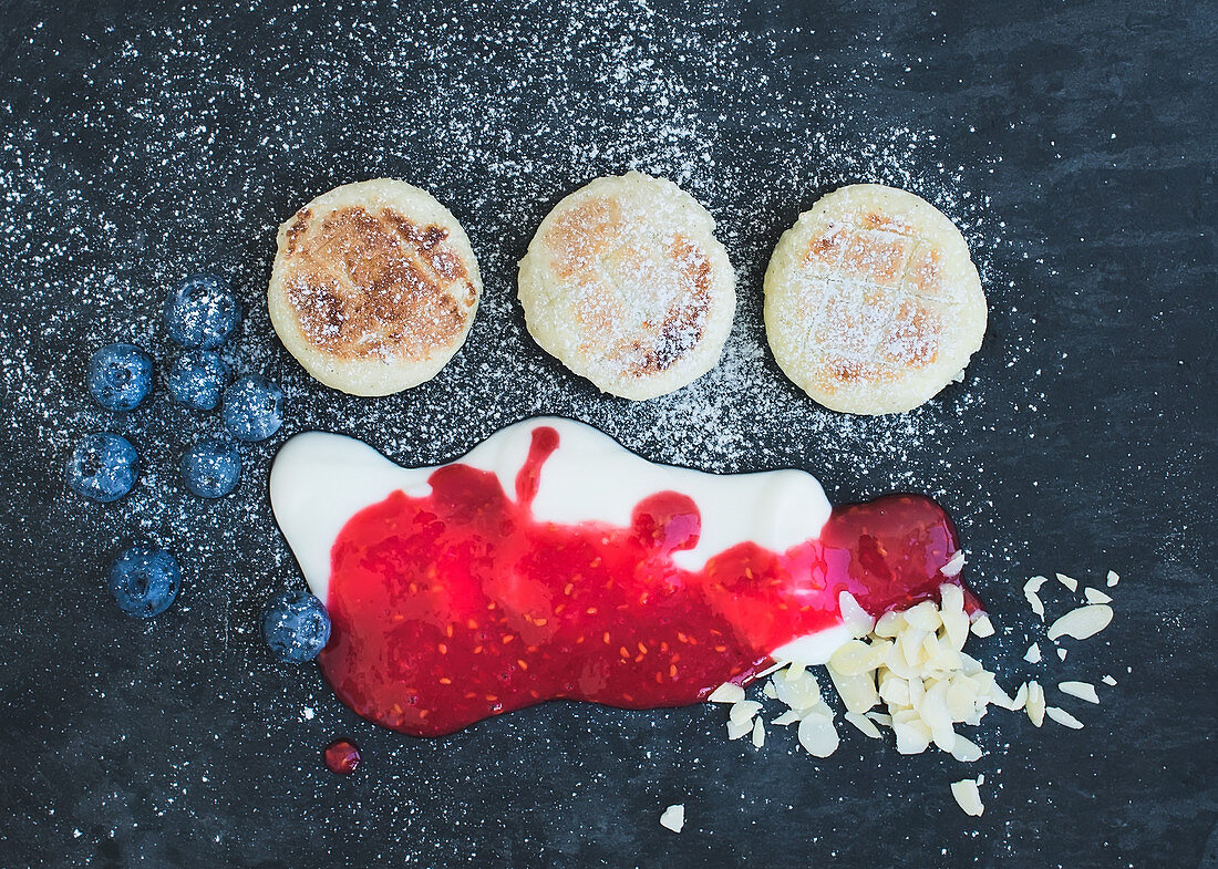 Frühstück mit Pancakes, Joghurt, Himbeermarmelade, Heidelbeeren und Mandelblättchen