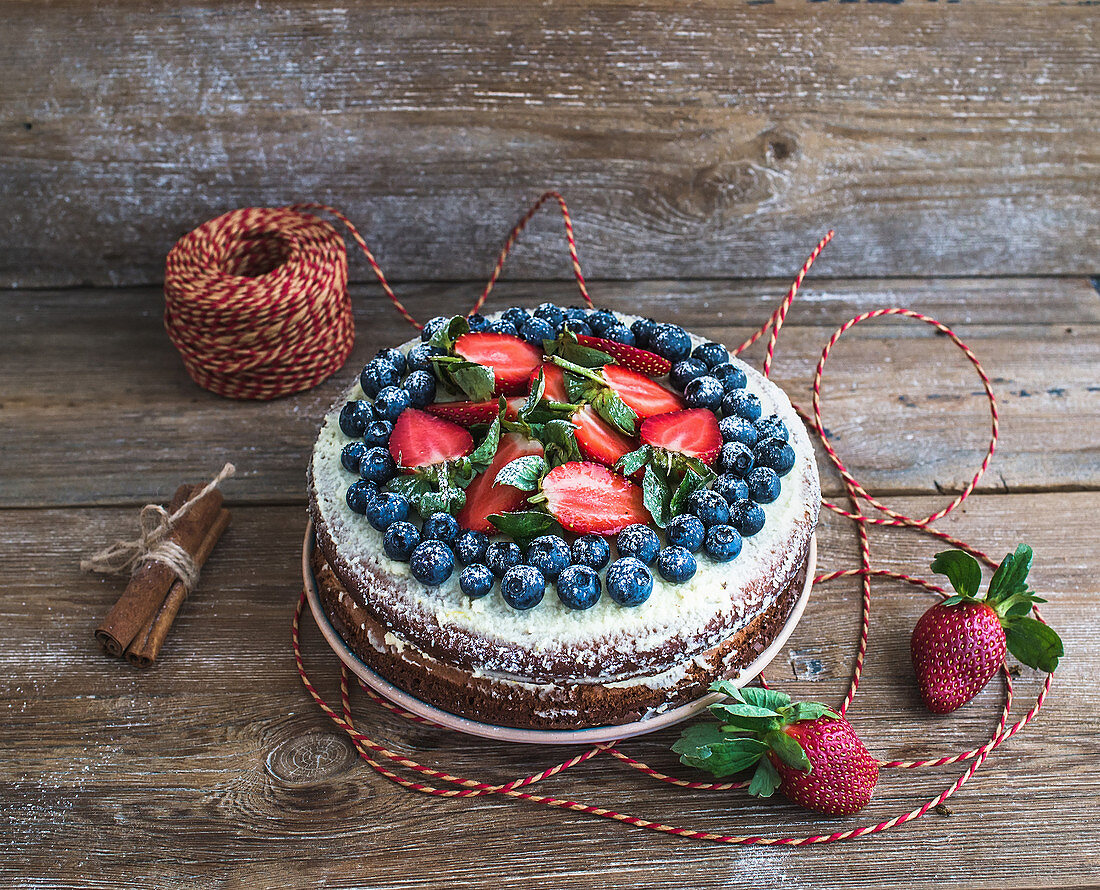 Rustic spicy ginger cake with cream-cheese filling, fresh strawberries and blueberries