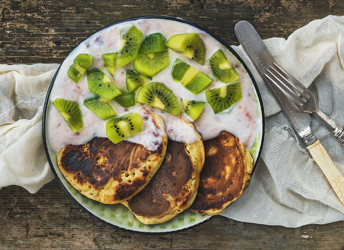 Rustic breakfast set with fluffy pancakes with strawberry yogurt and fresh kiwi