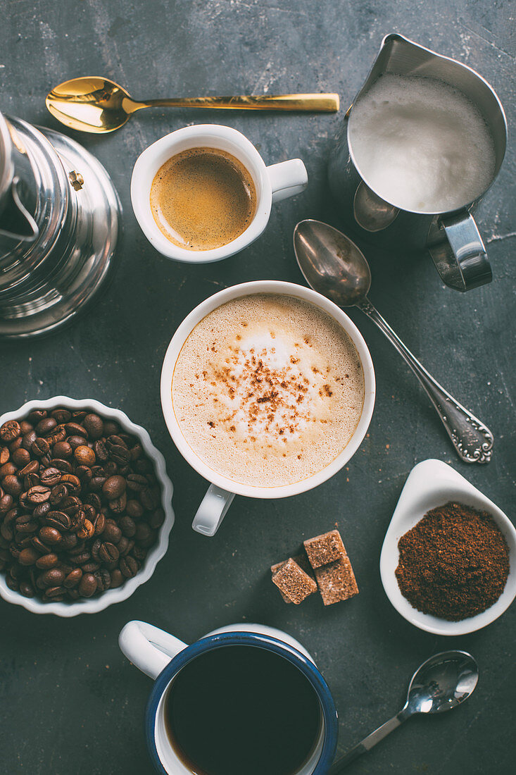 Verschiedene Kaffeespezialitäten mit Zutaten und Utensilien (Aufsicht)