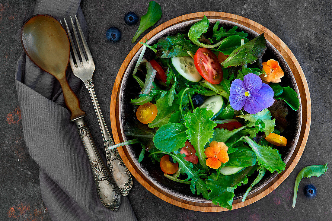 Frühlingssalat aus verschiedenen Blattsalaten mit Tomaten, Gurken und Essblüten