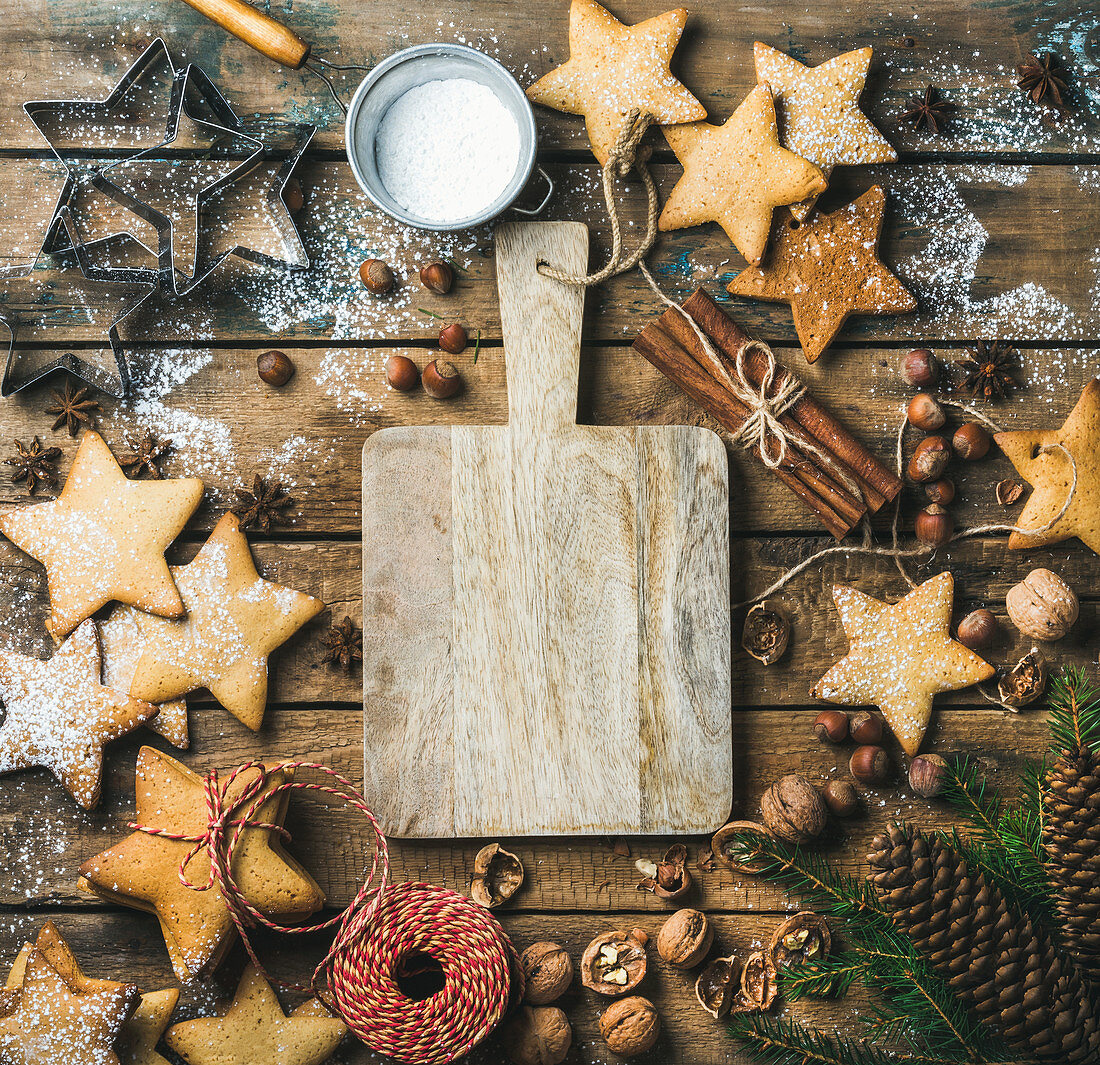 Gingerbread cookies, sugar powder, nuts, spices, baking molds, fir-tree branch, pine cones on rustic background