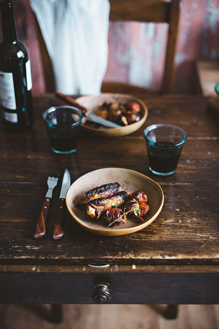 Gegrillte Rippen und Würstchen mit Rotwein auf rustikalem Holztisch