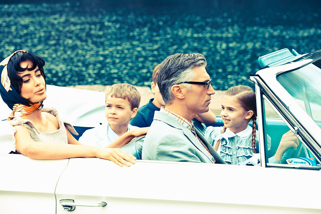 Familie mit drei Kindern in einem Cabrio