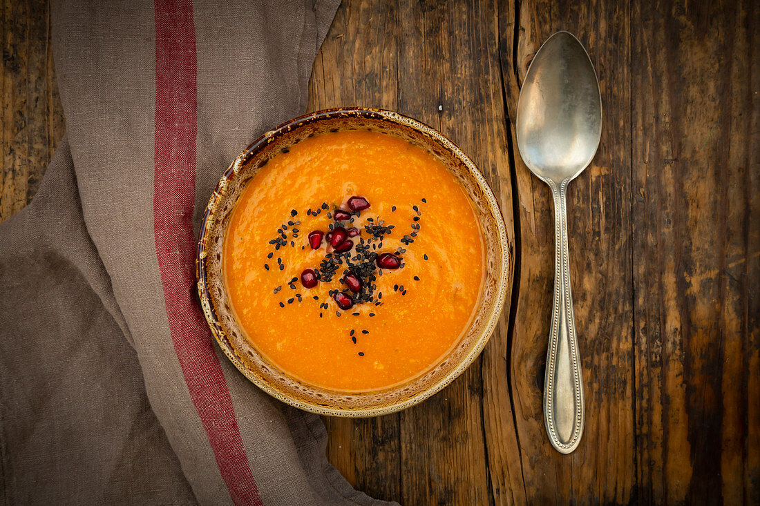 Orientalische Karotten-Ingwer-Kokos-Suppe mit schwarzem Sesam und Granatapfelkernen