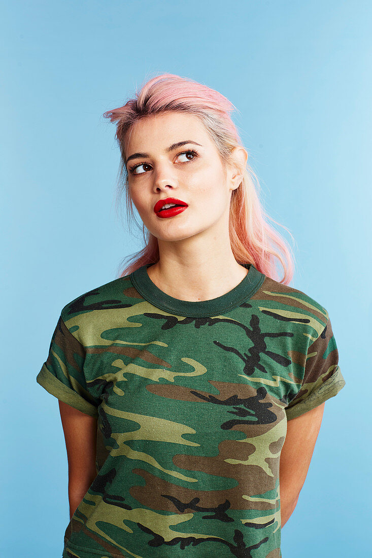 A young woman with pink hair wearing a camouflage t-shirt