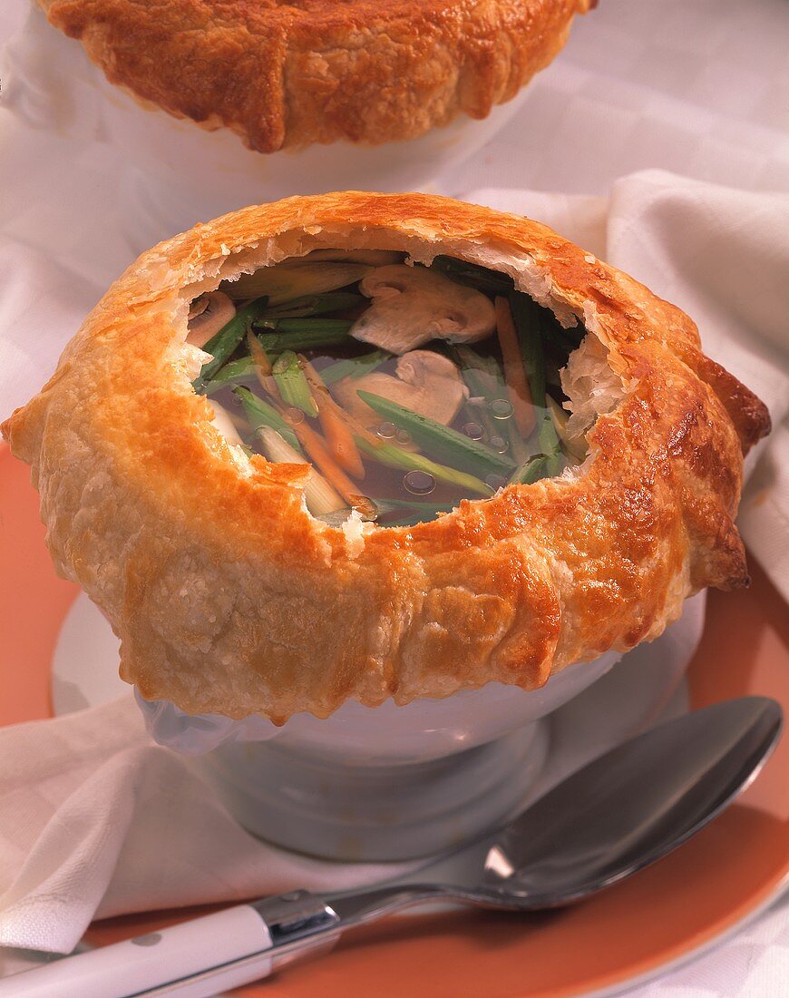 Vegetable and mushroom soup under puff pastry topping