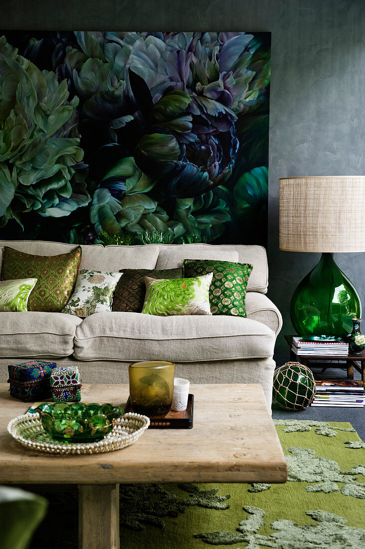 View over wooden table to sofa with scatter cushions and painting