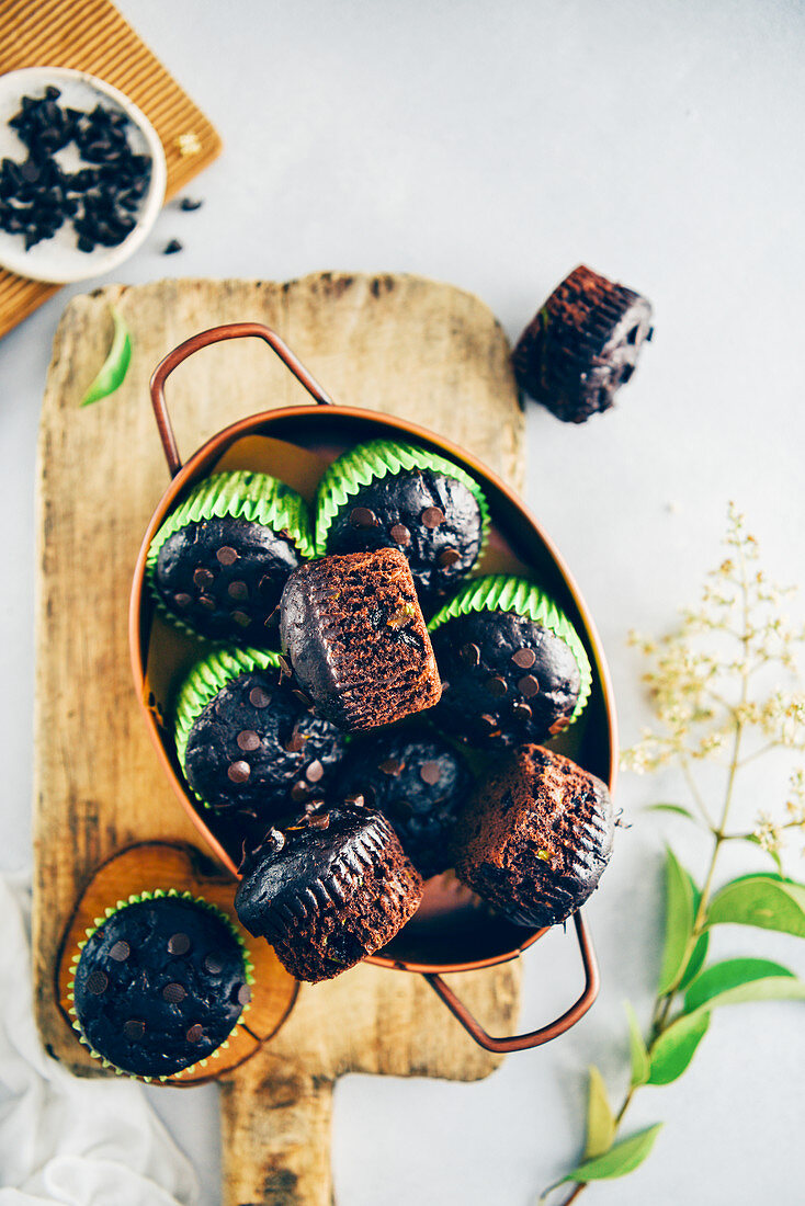 Healthy chocolate zucchini muffins in a copper pan served on a wooden cutting board