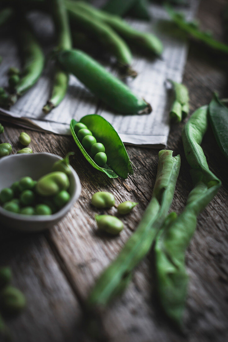 Green peas and green beans on a rustic wooden table