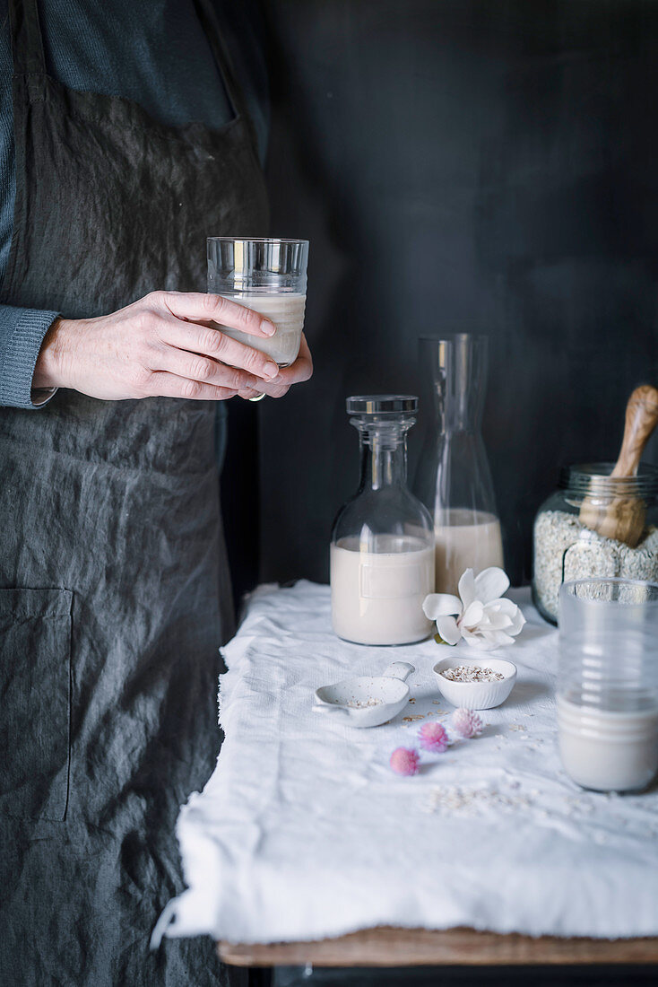 A woman holding a glass of Homemade Oatmeal milk