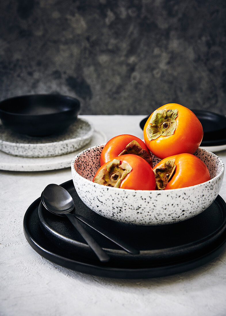 Fresh persimmon in a bowl on a marble background